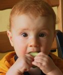 Photo of Andrew sitting on his chair eating some cucumber